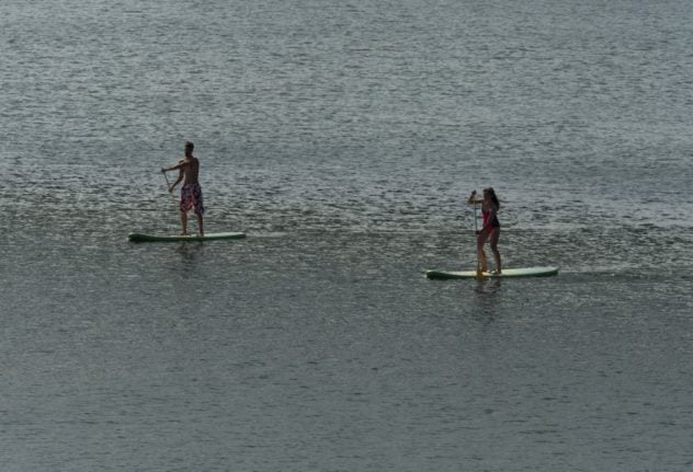 People doing stand-up paddleboarding on the Old Danube, a subsidiary of the Danube river, in Vienna.