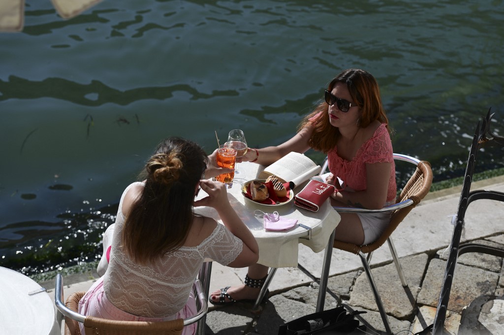 Two women enjoy an aperitivo drink by Venice's Grand Canal. 