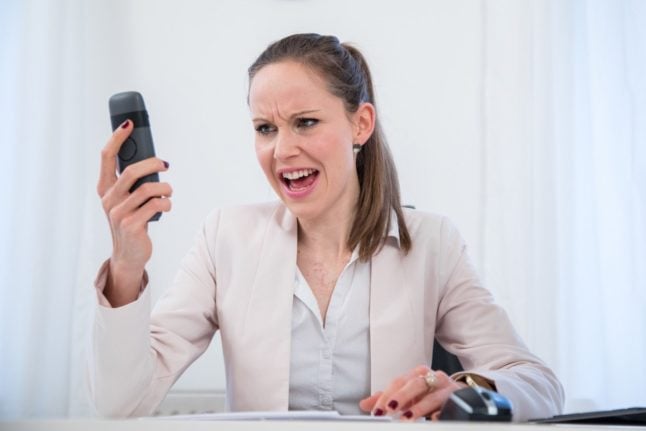 A woman shouts down the phone in an office.