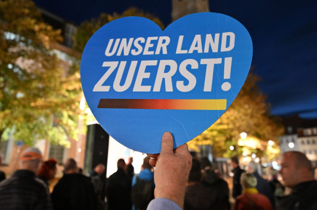 A man holds a heart with the slogan "Our country first!" during a rally of the AfD in Thuringia in October, 2022.