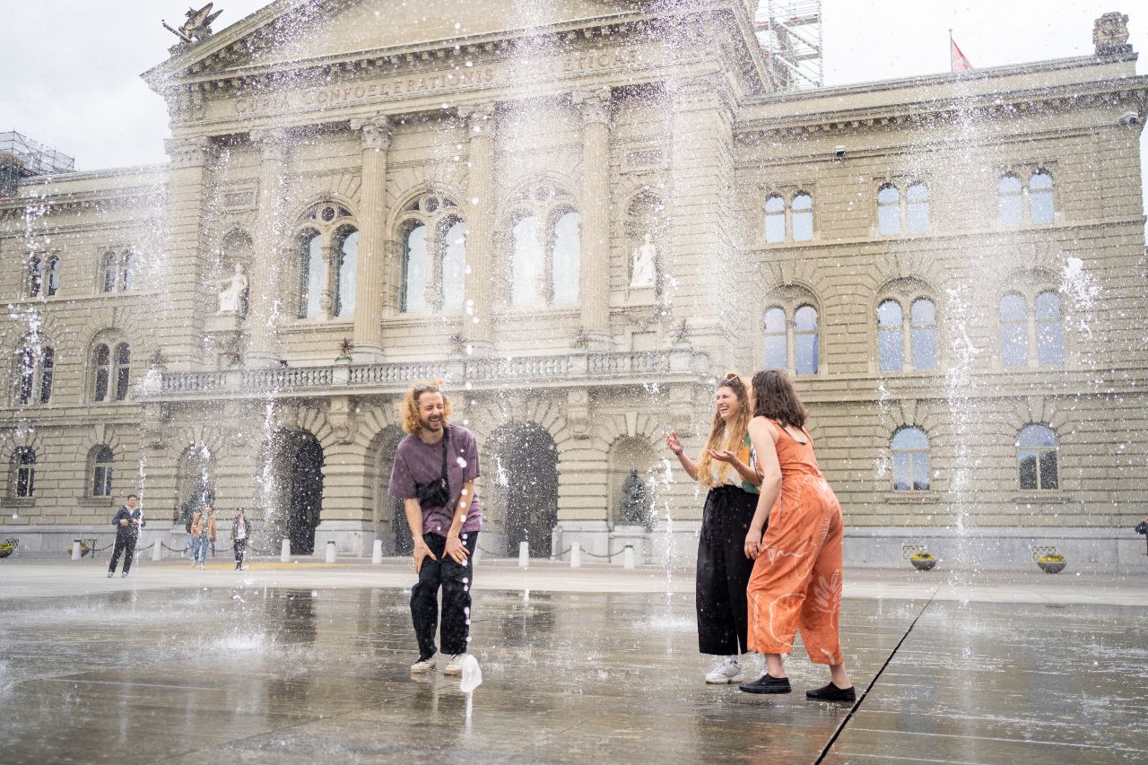 People enjoy the fountains in Bern at Bundesplatz.