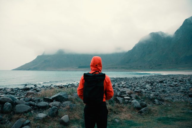 Pictured is a person on a beach in Lofoten in the rain.