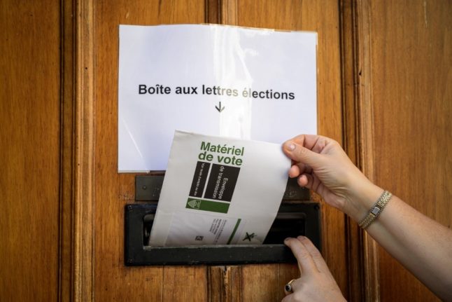 A woman inserts her postal voting envelope into the door of the polling station in Lausanne on September 29th, 2019.