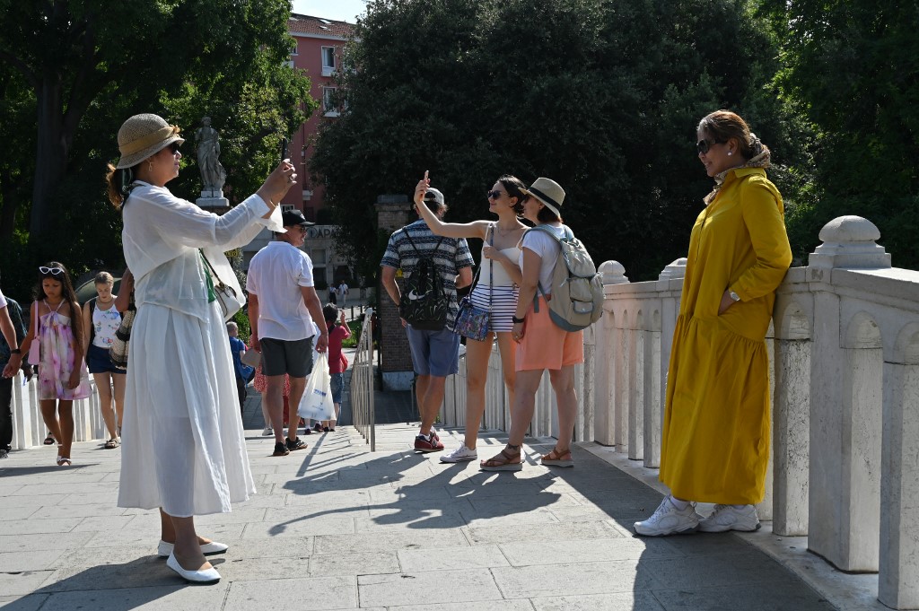 A view taken fon July 29, 2023 shows tourists taking photos on the Tolentini bridge in Venice. 