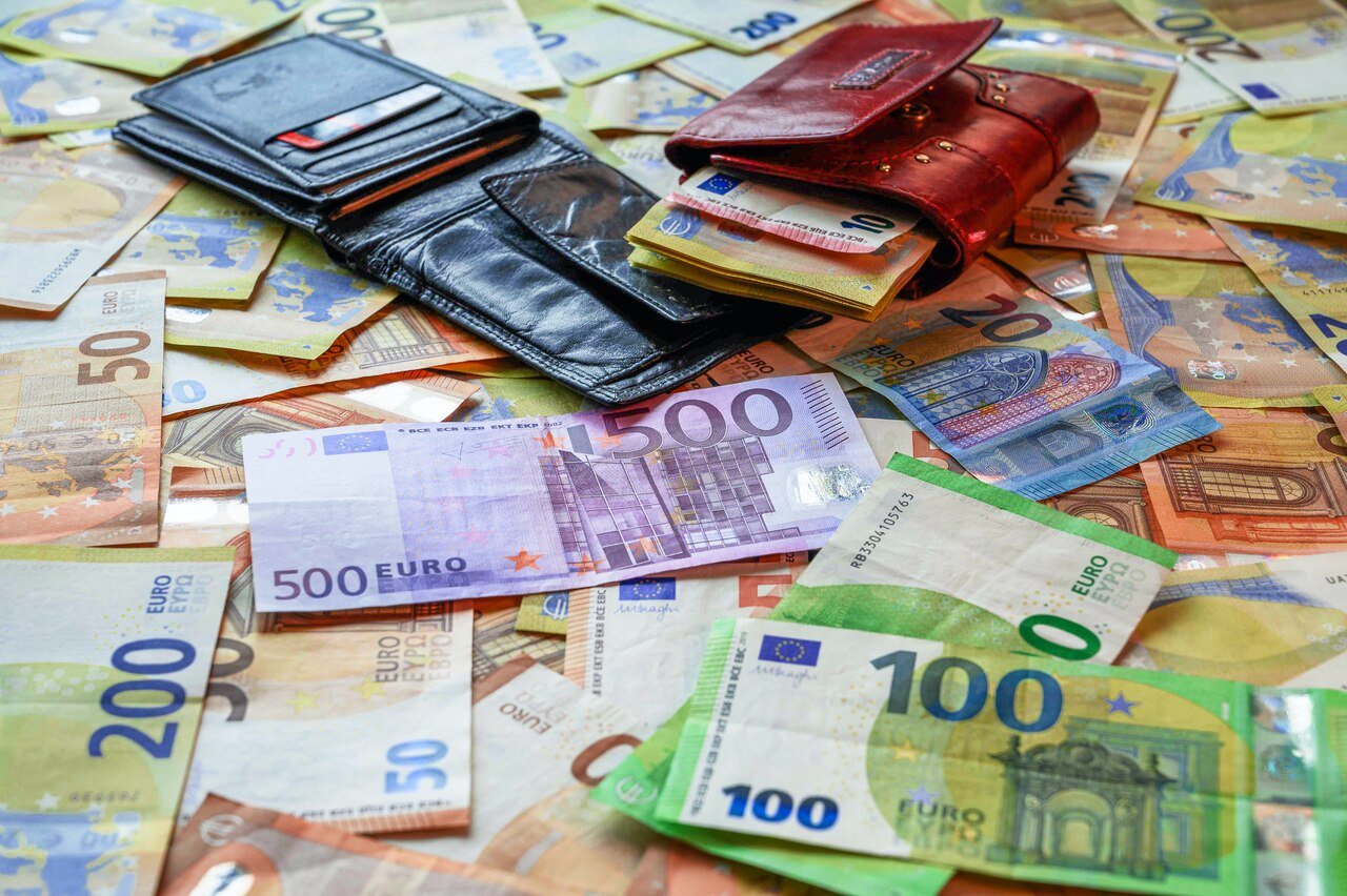 Hundreds of euros in bank notes are spread across a table and in two wallet
