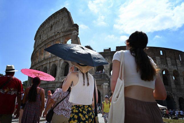 Tourists walk by Rome's Colosseum