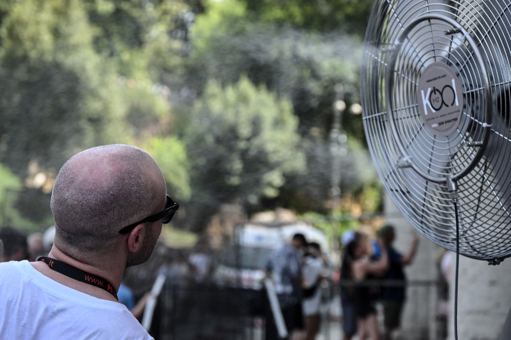 Man cools off in front of a fan in Rome
