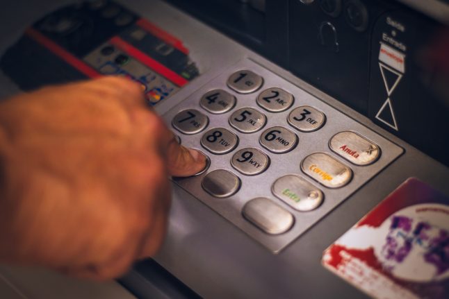 Pictured is a close up shot of a person inputting their pin on a ATM.