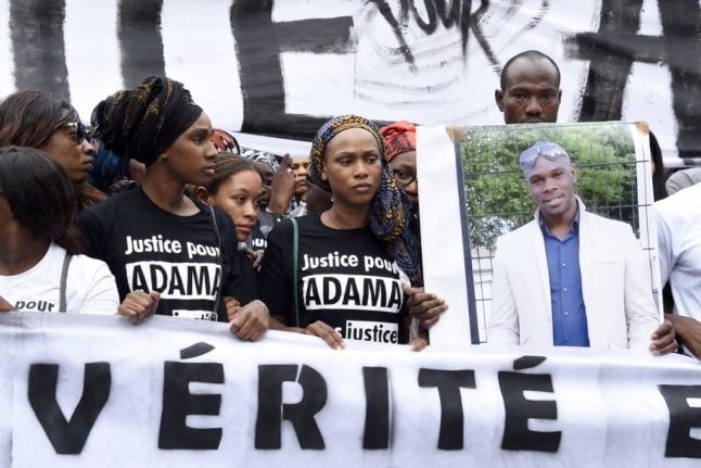 Adama's sister, Assa (2nd R) looks on next to a man holding a placard with a portrait of Adama Traore during a march to protest the death of Adama Traore, in Paris