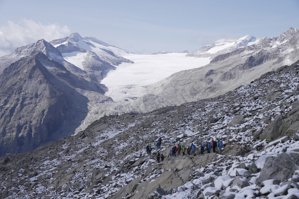 Legambiente members hiking down from Presana pass towards the Val Genova with the Adamello glacier in the background on September 1st, 2023. 