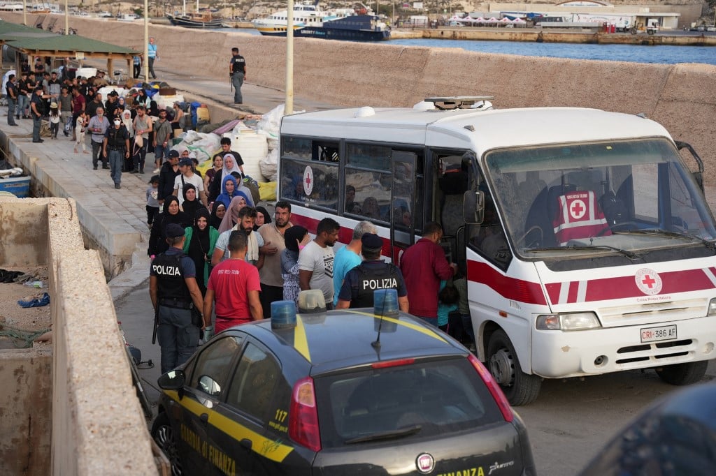 Migrants board an Italian Red Cross vehicle after arriving on the Italian island of Lampedusa, on September 18, 2023.