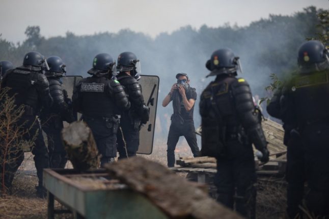 A protestor faces down French gendarmes as they begin to clear a protest site.