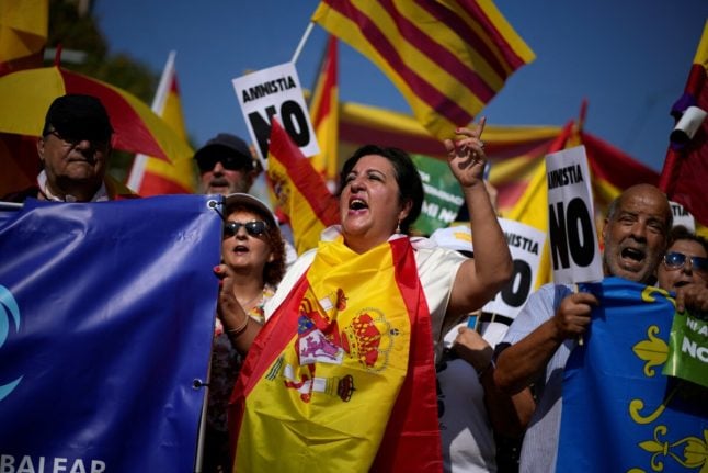 Protesters hold Spain's flags and 'No to amnesty' signs during a right-wing protest against plans to grant Catalan separatists an amnesty in order to form Spain's next government, in Barcelona on October 8, 2023.