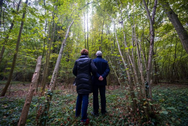 A couple stands in front of a group of trees to choose a place where they will rest after their death, in a forest in eastern France.