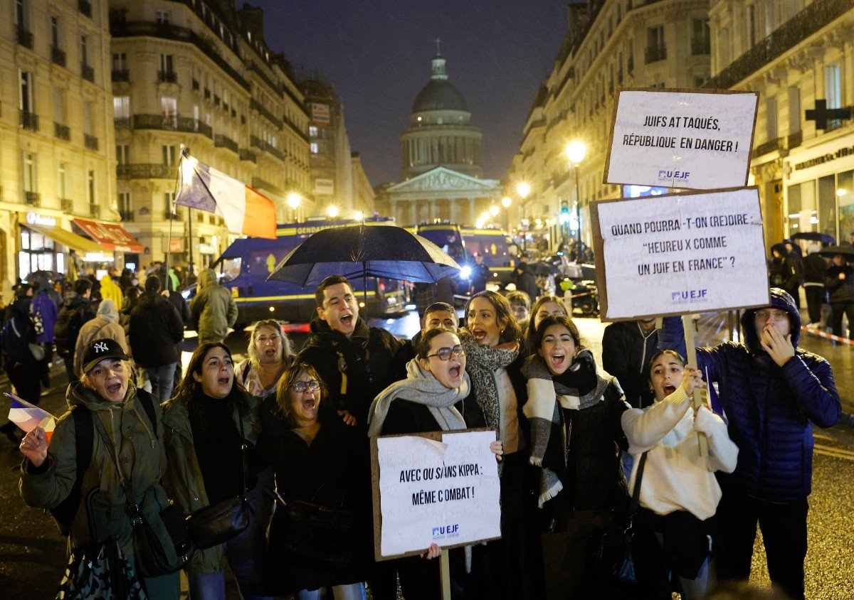Protesters holding a placard which reading "Anti-Semitism kills" (C), participate in a march against anti-Semitism in Paris