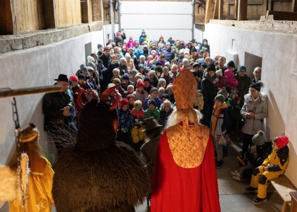 A rapt audience gazes at Saint Nicholas and the Krampus.
