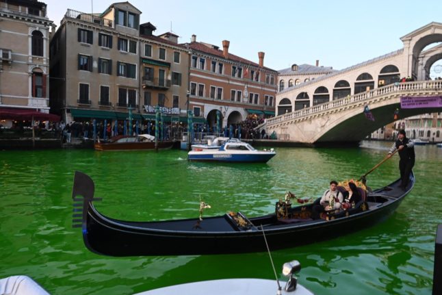 A gondola cruises on the Grand Canal after Extinction Rebellion (XR) activists poured fluorescein near the Rialto bridge in Venice to turn the water green during a protest against the COP28 'fail' on climate