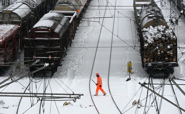 This 2021 file photo shows a man in high-visibility clothing walking over snow-covered railtracks in a freight railway yard in Munich.