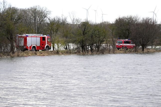 Fire department vehicles drive along a flooded bank of the Helme river in Oberroeblingen, eastern Germany