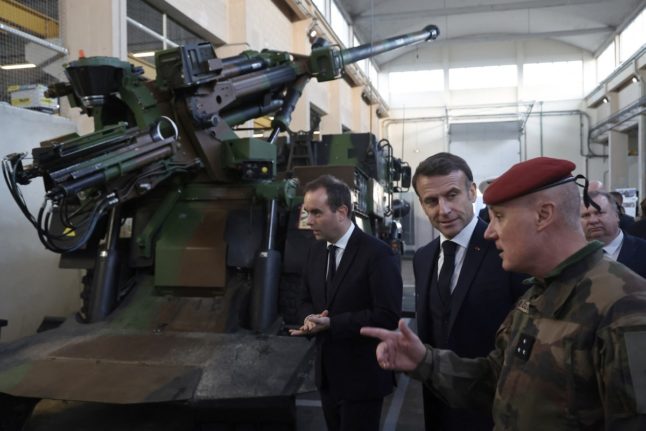 French President Emmanuel Macron (C) and French Minister for the Armed Forces Sebastien Lecornu (C) inspect a Caesar self-propelled artillery system during a visit to the Cherbourg naval base