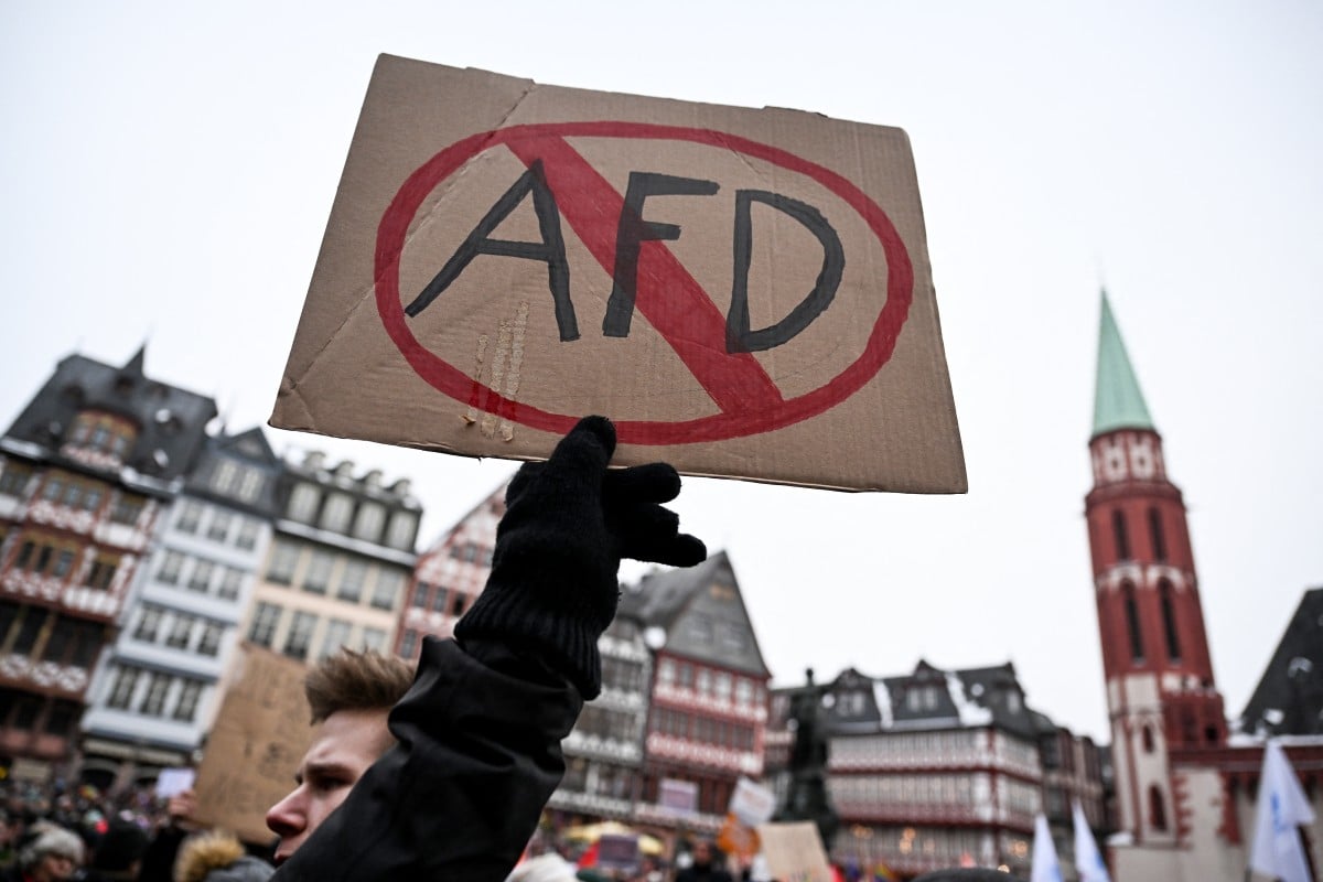A demonstrator holds a placard with crossed-out AfD sign, referring to Germany's far-right Alternative for Germany (AfD) party during a demonstration against racism and far right politics in Frankfurt am Main