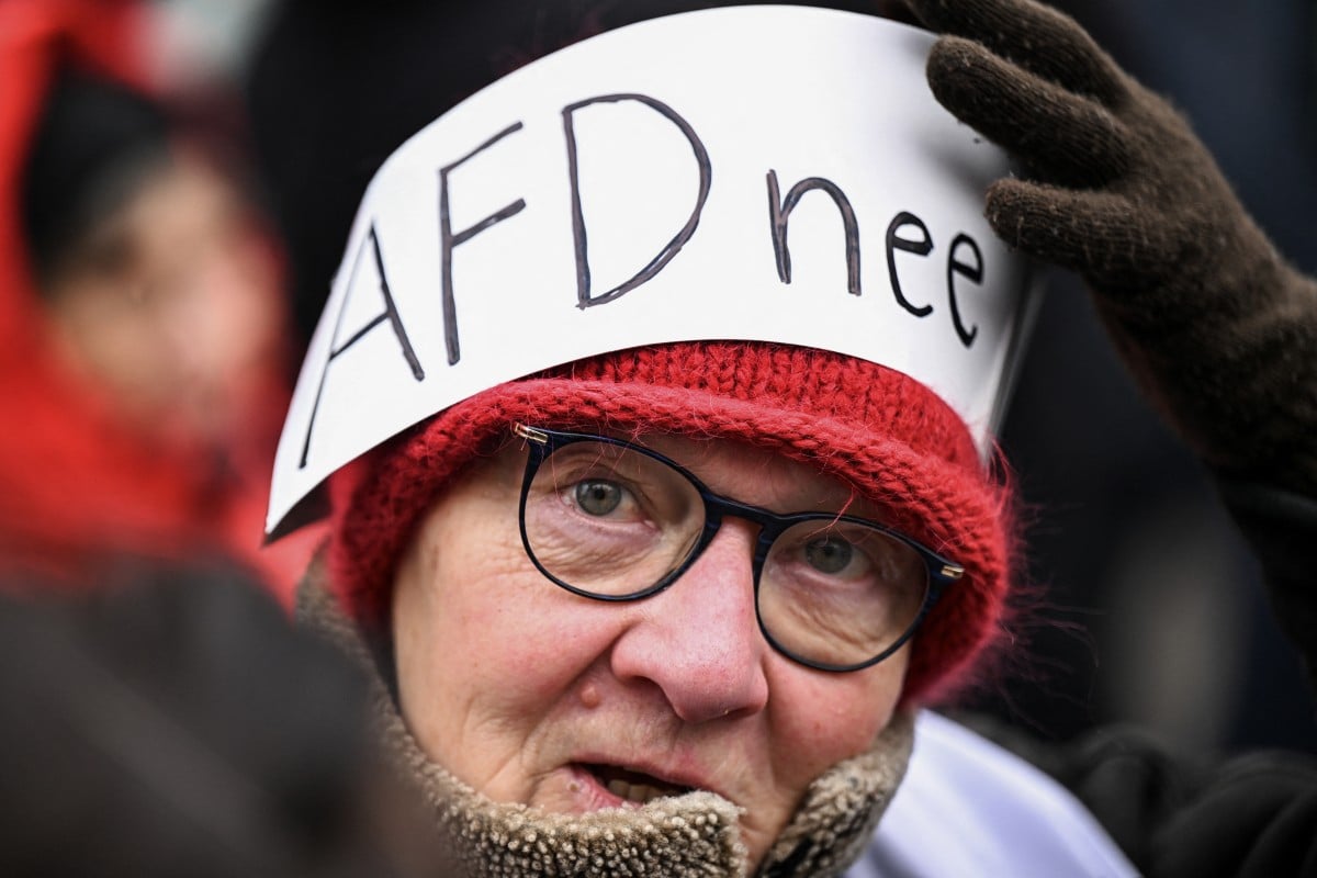 A demonstrator holds a placard on her head reading "AfD - no"