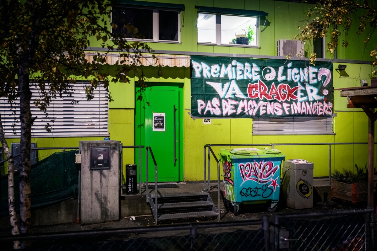 This photo taken on December 8, 2023 shows a banner which reads "front line is going to crack without financial means" outside the Quai 9 safe injection room, in downtown Geneva. 