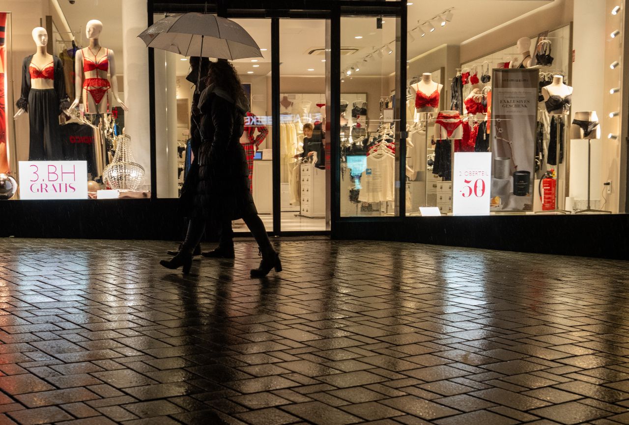 Pedestrians walk in the rain past shops in Ulm, Baden-Württemberg.