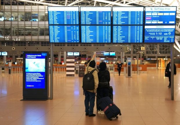 Passengers look at the departures board at Frankfurt airport.