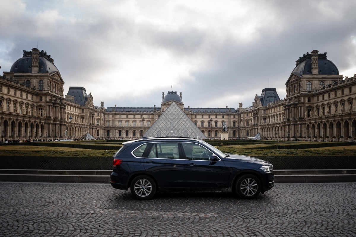 A car drives past the Louvre Museum in Paris city centre