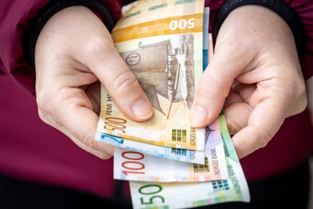 Pictured is a person holding a handful of kroner.