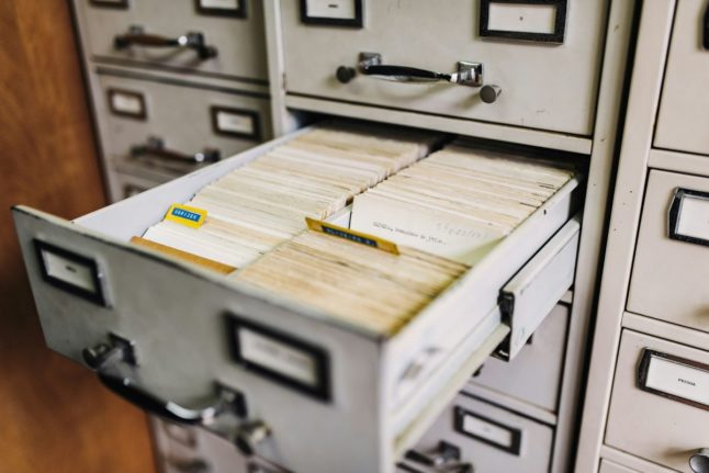 Pictured is a stock photo of a filing cabinet full of papers.