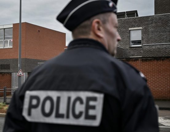 This photograph taken in Chenove, in central-eastern France, on March 18, 2024, shows a police officer standing guard outside the Edouard Herriot secondary school before the visit of French Minister for Education and Youth, who is to meet the teaching staff following threats