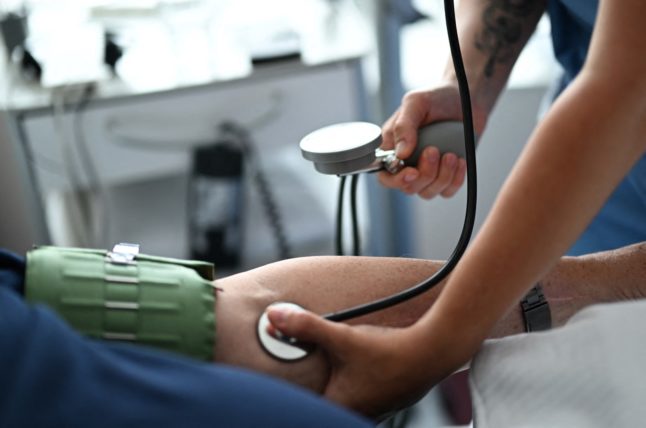 A nursing assistant measures the blood pressure of a patient