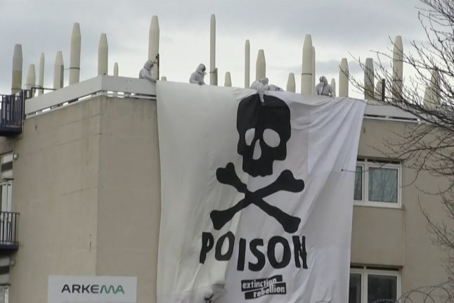 Extinction Rebellion and Youth for Climate activists deploying a giant banner depicting a skull and bones, atop a structure inside the Arkema chemical plant