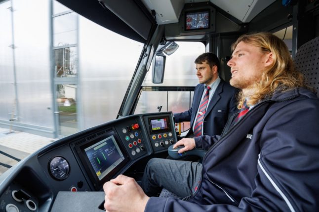 Christopher Hecht (L), driving instructor at Nuremberg's public transport company VAG, is seen next to university student Benedikt Hanne in the driver's cab of a tram in Nuremberg,