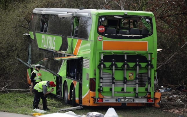 Police officers work next to a damaged coach on the A9 motorway, at the scene of an accident where four people were killed