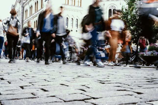 Pictured is a blurred image of crowds walking past Norway's parliament.