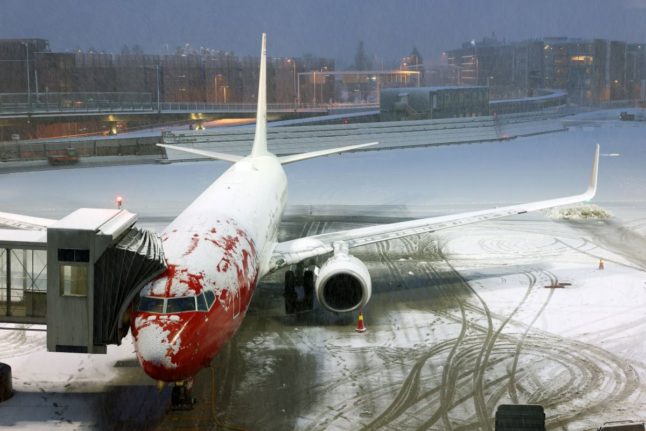 Pictured is a plane covered in snow in Oslo.