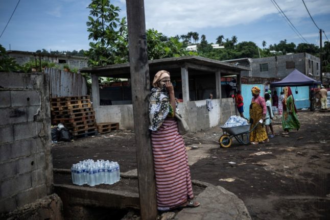 Residents collect packs of bottled drinking water from a distribution point in the Majicavo district in Mamoudzou on the French Indian Ocean island of Mayotte