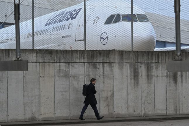 A person walks past a parked Lufthansa airplane at Frankfurt international airport.