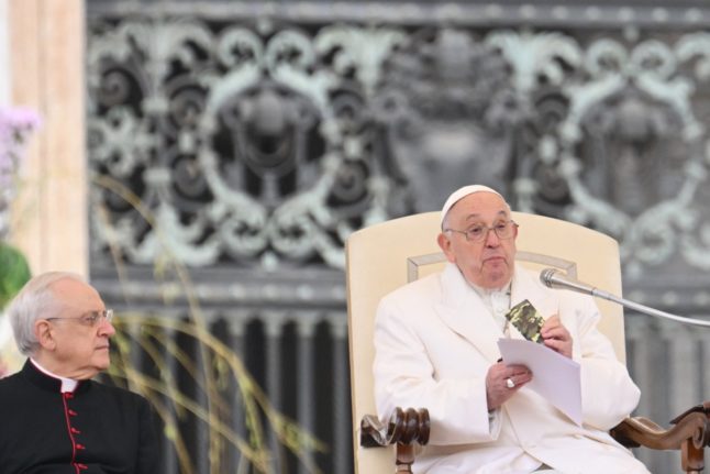 Pope Francis (R) holds a small new Testament from a 23-year old-soldier who died in Ukraine during his weekly general audience in St.Peter's square at the Vatican on April 3