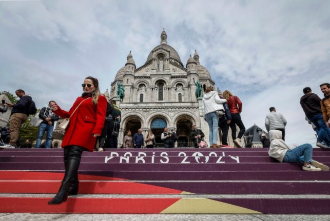 People walk down the stairs painted in the colours of the upcoming Paris 2024 Olympics in front of the Sacre Coeur Basilica on top of the Montmartre hill in Paris.