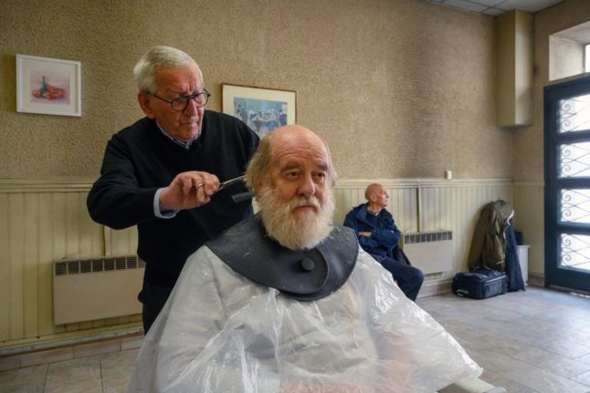 Hairdresser Roger Amilhastre, 90, cutting a customer's hair at his salon