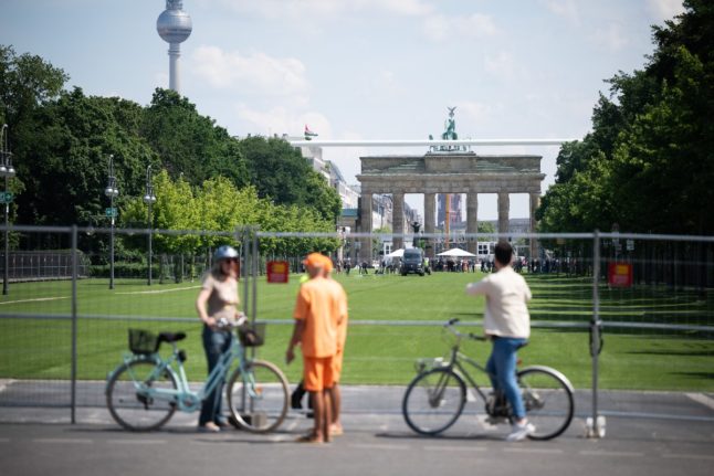 Visitors stand at the barrier in front of the fan zones for the 2024 European Football Championship around the Brandenburg Gate on Straße des 17. Juni in Berlin.