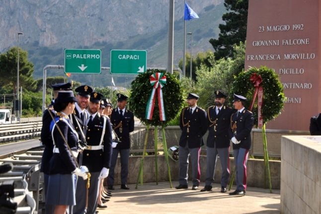 Italian policemen stand in front of the memorial for anti-mafia judge Giovanni Falcone on the motorway to Palermo