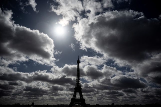 The sun shining between clouds over the Eiffel Tower in Paris