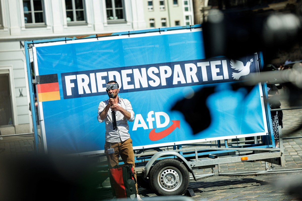 A man films with a smartphone in front a placard of German far-right Alternative for Germany AfD party with the lettering 'Freedom Party' during a campaign event for the upcoming European Parliament elections, and ahead of Saxony's municipal and state elections, in Dresden, eastern Germany on May 1, 2024.