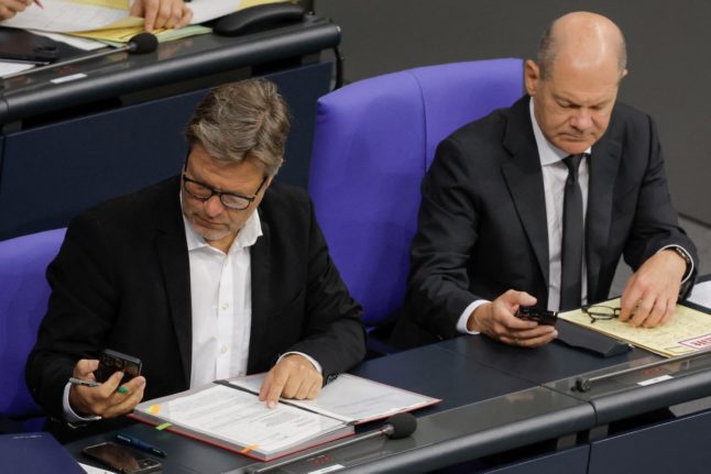 German Minister of Economics and Climate Protection Robert Habeck (L) and German Chancellor Olaf Scholz both look at their smartphone during a session at the Bundestag