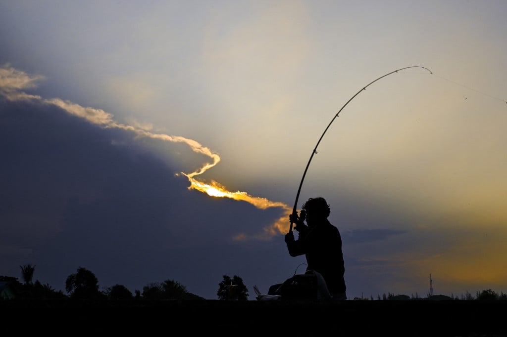 A fisherman casts his rod at dawn